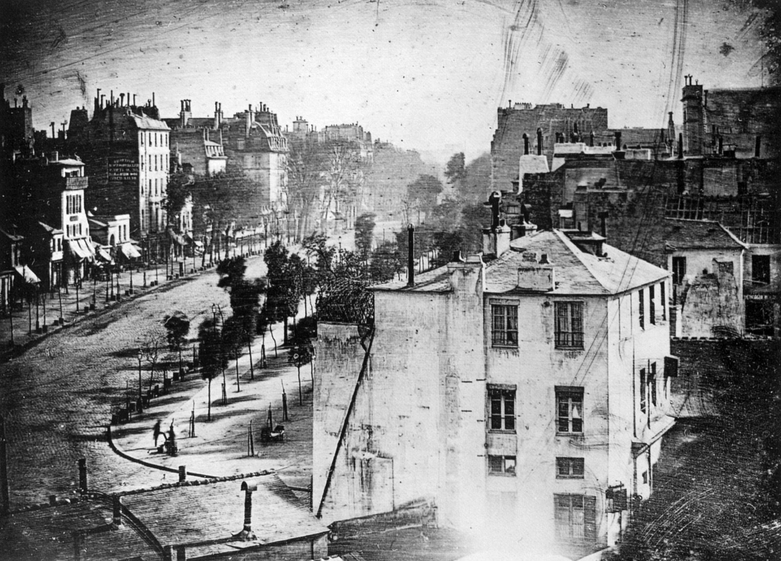 The 1838 daguerreotype Boulevard du Temple, showing an apparently empty Paris street with a man having his boots polished barely visible at the lower left corner.