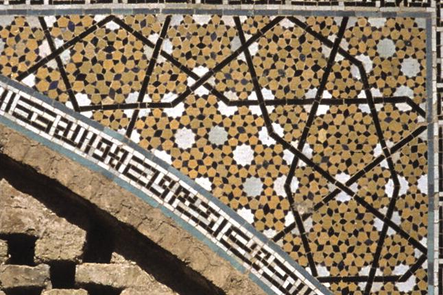 A girih tile geometric pattern on a spandrel from the Darb-i Imam shrine in Isfahan, Iran, built in 1453, bordered by a Kufic calligraphy band, the tiling that physicists Peter Lu and Paul Steinhardt cited as evidence of medieval quasicrystalline design.
