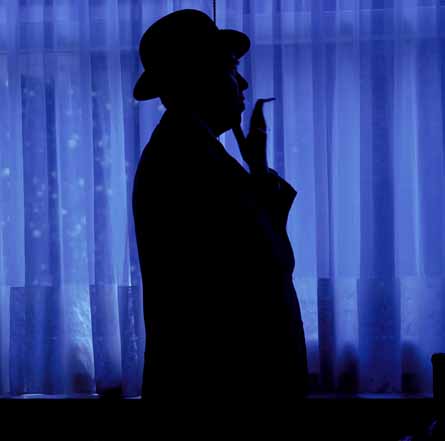 Rene Magritte photographed by Lothar Wolleh, wearing a dark coat and bowler hat against a plain background.
